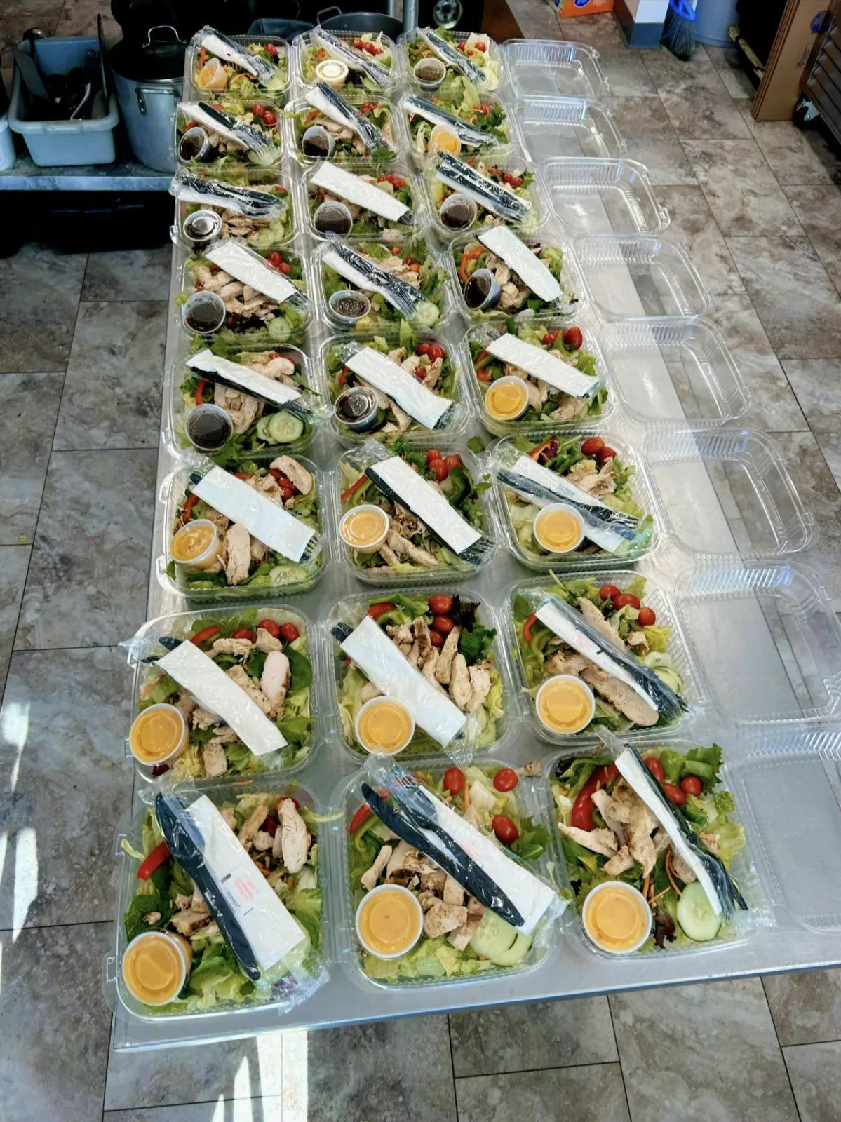 Grilled chicken salads, boxed with dressing and cutlery